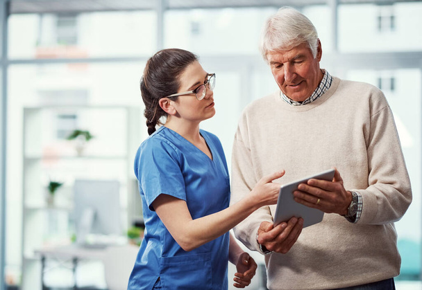 Laissez-moi vous montrer rapidement. une jeune infirmière et sa patiente âgée regardant une tablette à la maison de retraite - Photo, image