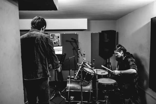 Пристрасний та інтенсивний молодий вокаліст та барабанщик розв'язують сиру енергію під час інтенсивного виконання металу у репетиційній кімнаті
 - Фото, зображення