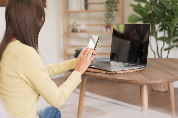 Концепція релаксації, молода жінка перевіряє онлайн продажі доходів по телефону, сидячи, щоб розслабитися на підлозі
. - Фото, зображення
