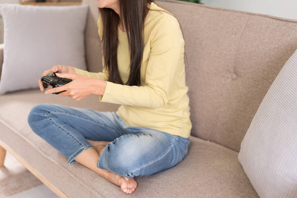 Concept de détente, Jeune femme assise sur le canapé pour jouer à des jeux vidéo avec console joystick. - Photo, image