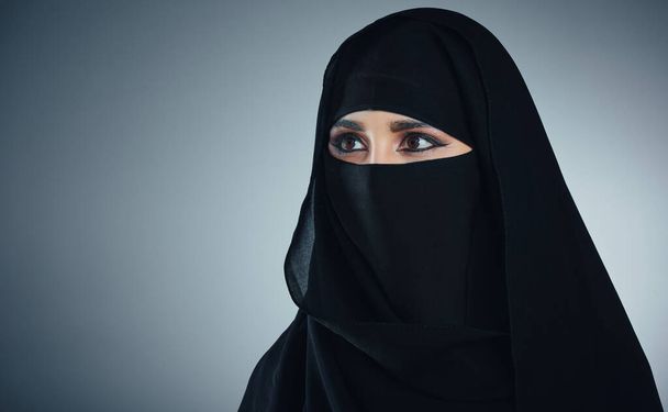 Güzelliğinin üstünü örtüyor. Genç Müslüman bir iş kadınının gri bir arka planda çekilmiş bir fotoğrafı. - Fotoğraf, Görsel