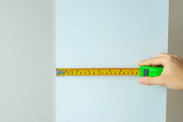 Чоловік рука використовує стрічкову міру для вимірювання меблів вдома. DIY, Дизайн інтер'єру, ремонт та вдосконалення концепції будинку або квартири
 - Фото, зображення