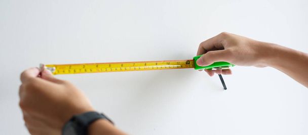 Чоловік рука використовує стрічковий вимір для вимірювання з фон стіни в домашніх умовах. DIY, Дизайн інтер'єру, ремонт та вдосконалення концепції будинку або квартири
 - Фото, зображення