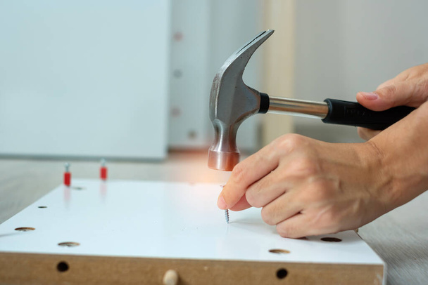 man using hammer hammering a nail into wooden boards, assembling or repairing furniture at home. DIY, Renovation, repairing and development home or apartment concepts - Photo, Image