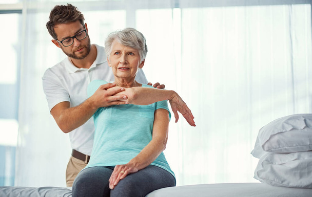 Your joints are in good order. a senior woman working through her recovery with a male physiotherapist - Foto, Imagen