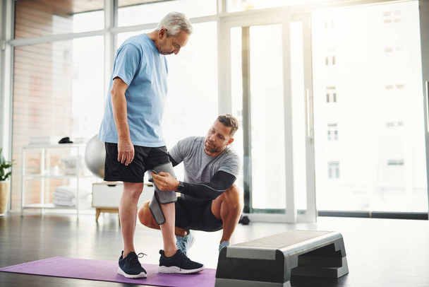 Laten we je lichaam weer laten functioneren 100. Een jonge mannelijke fysiotherapeut die een oudere patiënt helpt bij het herstel. - Foto, afbeelding