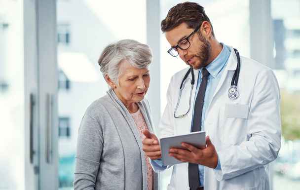 J'ai fait un diagnostic clair sur votre état... un médecin discutant de quelque chose sur une tablette numérique avec un patient âgé dans une clinique - Photo, image