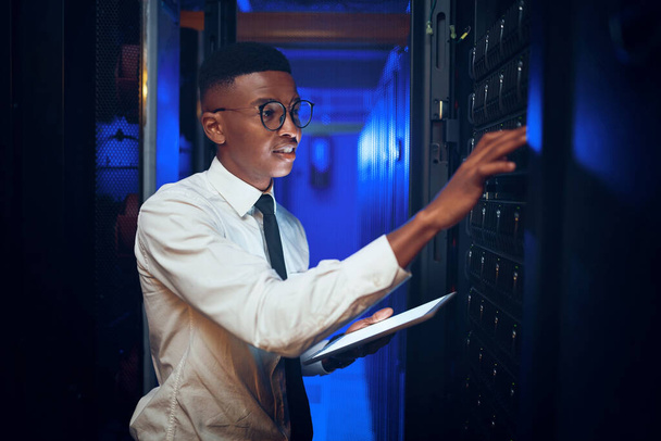 He knows his way around big data. a young man using a digital tablet while working in a server room - Foto, imagen