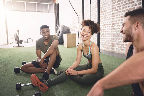 Wir kommen wegen der Übung und der Gespräche. drei sportliche junge Leute im Gespräch, während sie in einem Fitnessstudio zusammensitzen - Foto, Bild