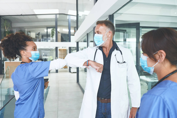 Новий звичайний рукостискач. красивий зрілий лікар стоїть і лікоть стукає свою медсестру як привітання в клініці
 - Фото, зображення