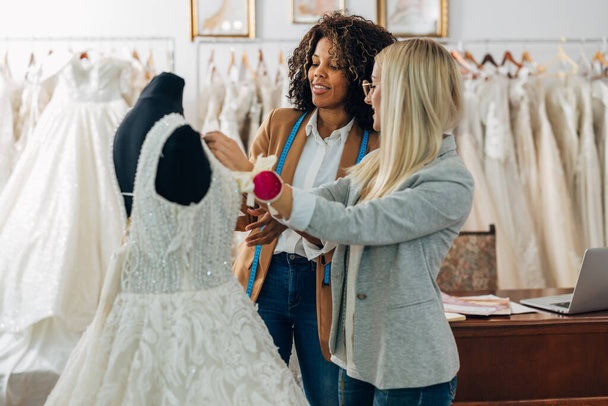 Two women work together on a new wedding dress. - Foto, afbeelding