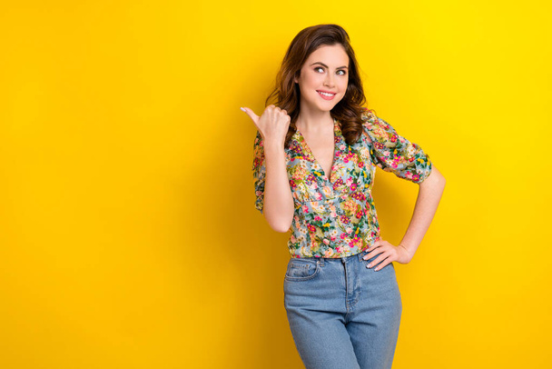 Photo of pretty thoughtful lady wear retro flower print blouse looking showing thumb empty space isolated yellow color background. - Фото, изображение