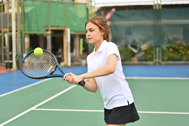 Prise de vue d'une jeune joueuse de tennis sportive frappant une balle avec une raquette pendant le match. Fitness, sport, concept d'exercice. - Photo, image