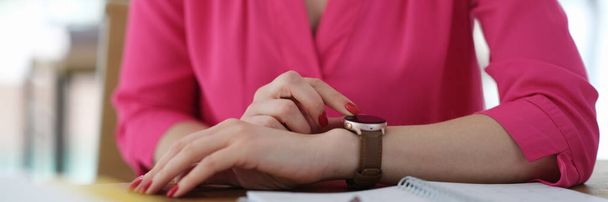 Mujer de negocios ajustando el reloj de pulsera en la mesa en primer plano de la oficina. Concepto de gestión del tiempo - Foto, Imagen