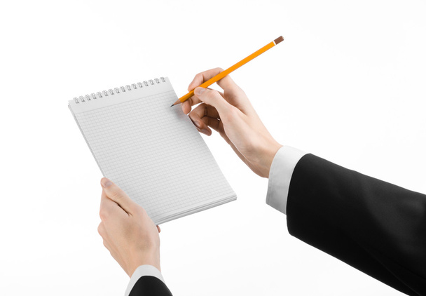 Business and reporter topic: the hand of a journalist in a black suit holding a notebook with a pencil on a white background isolated - Φωτογραφία, εικόνα