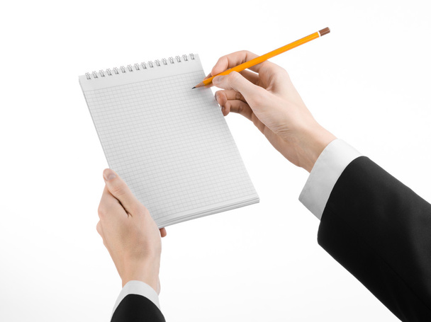 Business and reporter topic: the hand of a journalist in a black suit holding a notebook with a pencil on a white background isolated - Φωτογραφία, εικόνα