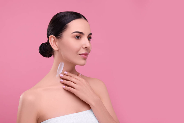 Beautiful woman with smear of body cream on her neck against pink background, space for text - Zdjęcie, obraz