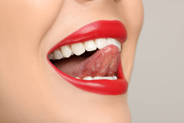 Woman showing her tongue on light background, closeup - Photo, Image
