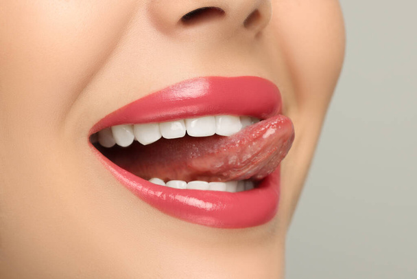 Woman showing her tongue on light background, closeup - Zdjęcie, obraz