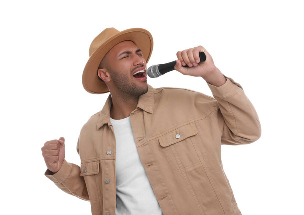 Handsome man with microphone singing on white background - Photo, Image