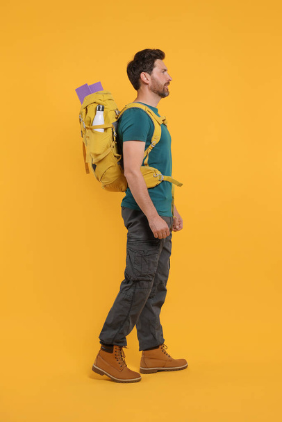 Człowiek z plecakiem na pomarańczowym tle. Turystyka aktywna - Zdjęcie, obraz