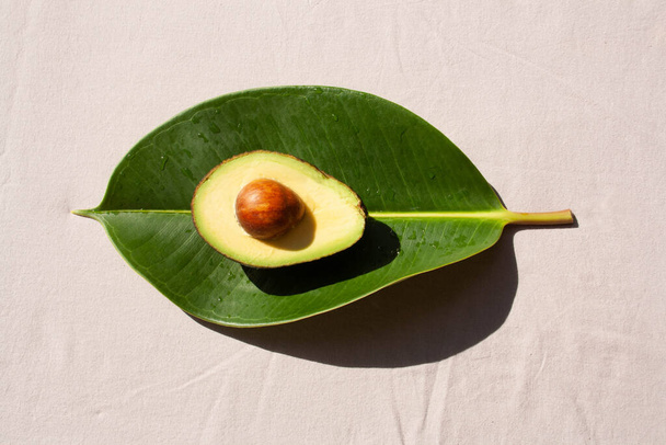 Avocado in Scheiben geschnitten auf einem grünen Blatt vor grauem Hintergrund. Blick von oben. Konzept natürliche Ernährung. - Foto, Bild