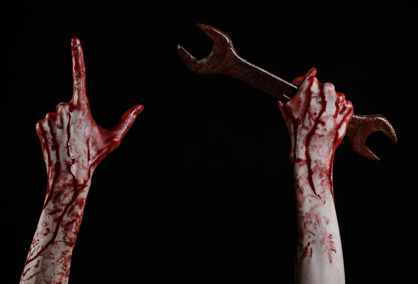 bloody hand holding a big wrench, bloody wrench, big key, bloody theme, halloween theme, crazy mechanic, murderer, psycho, violence, zombies, black background, isolated, revolution - Foto, imagen