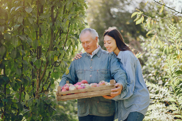 Senior with box of apple. Brunette in a blue shirt. Grandfather with grandaughter. - Foto, immagini