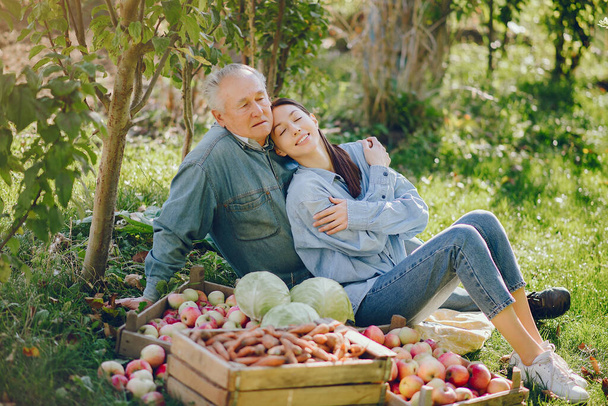 Senior with box of apple. Brunette in a blue shirt. Grandfather with grandaughter. - Foto, imagen