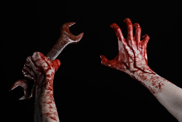 bloody hand holding a big wrench, bloody wrench, big key, bloody theme, halloween theme, crazy mechanic, murderer, psycho, violence, zombies, black background, isolated, revolution - Foto, immagini