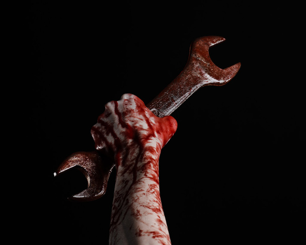 bloody hand holding a big wrench, bloody wrench, big key, bloody theme, halloween theme, crazy mechanic, murderer, psycho, violence, zombies, black background, isolated, revolution - Foto, Imagem