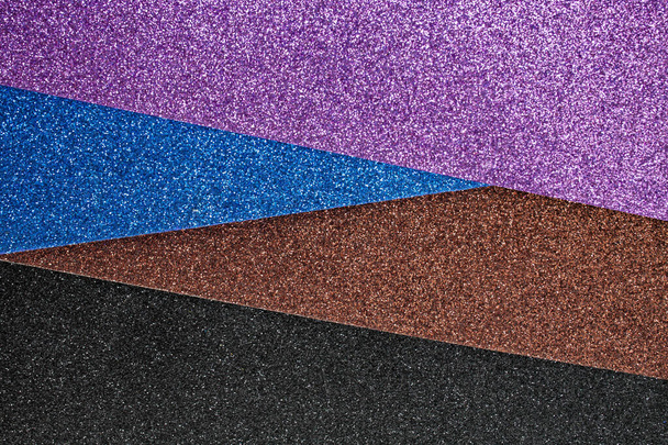 hojas de purpurina violeta, azul marrón y negro dispuestas en un ángulo, textura de enfoque suave - Foto, Imagen