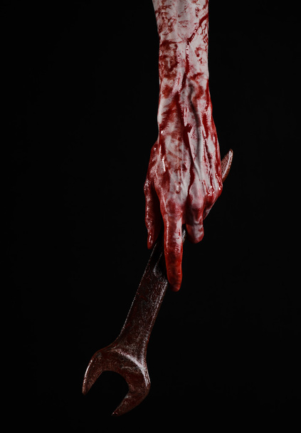 bloody hand holding a big wrench, bloody wrench, big key, bloody theme, halloween theme, crazy mechanic, murderer, psycho, violence, zombies, black background, isolated, revolution - Foto, Imagem
