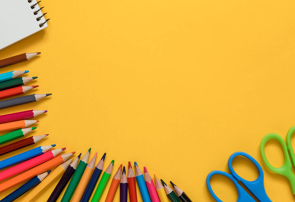 Világos színes ceruzák, jegyzetfüzet és olló sárga háttérrel. Vissza a tantervhez. Első látásra. Fénymásolási hely. - Fotó, kép