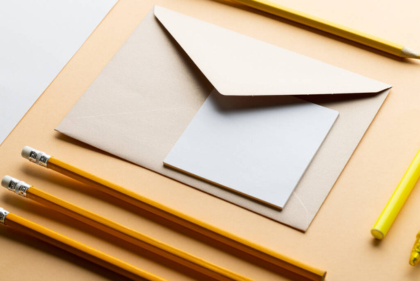 Flat lay of yellow pencils and marker, envelope and white paper with copy space on yellow background. School materials, writing, colouring, drawing, learning, school and education concept. - Foto, Imagen