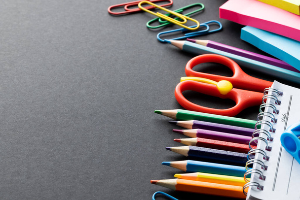 Close up of coloured pencils and school materials with copy space on black background. School materials, writing, colouring, drawing, learning, school and education concept. - Foto, Imagen