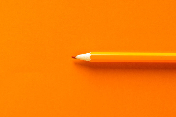 Close up of orange pencil with copy space on orange background. School materials, writing, colouring, drawing, learning, school and education concept. - Фото, зображення