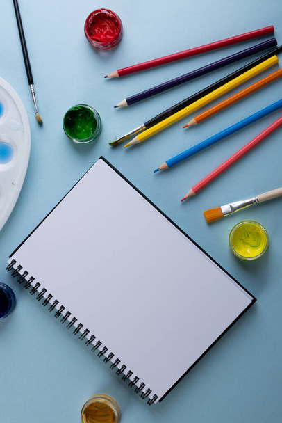 Close up of paints, pencils, notebook and brushes with copy space on blue background. Back to school, art, painting, school materials, learning, school and education concept. - Fotoğraf, Görsel