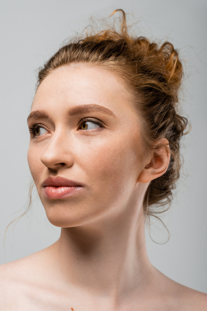 Portrait of young red haired and freckled woman with natural makeup and naked shoulders looking away and standing isolated on grey, natural beauty and individuality concept, Youth Culture - Foto, Imagem