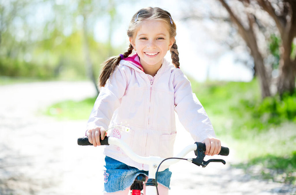 cuye little girl on her pink bike on the road. close-up - Foto, Imagen