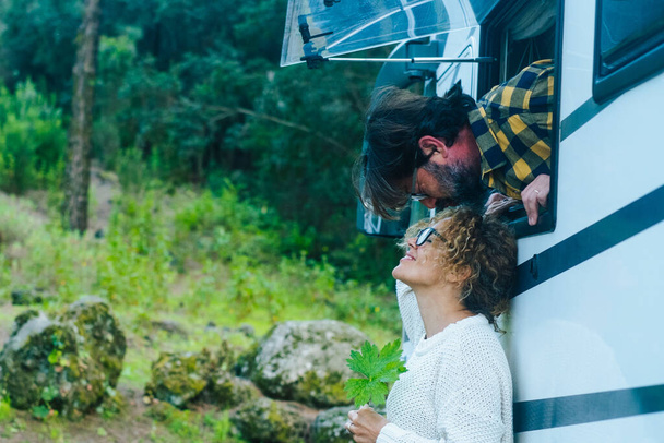 Счастливая взрослая пара веселится и любит целоваться снаружи фургона. - Фото, изображение