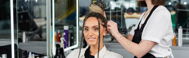 salon experience, tattooed hairdresser doing hair bun to female client with braids, cheerful women, client satisfaction, customer in salon, beauty service, feminine, hair make over, banner - Photo, Image