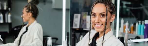 happy client in beauty salon, cheerful woman with hair bun looking at camera, customer satisfaction, hair salon, hairstyle, female client with braids, looking at camera, mirror refection, banner  - Photo, Image