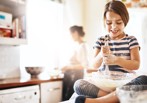 Messy, happy and child baking in the kitchen with parent for bonding, food and dessert. Funny young girl mixing flour in a bowl with chaos, energy or cooking with happiness while playing for learning. - Fotoğraf, Görsel