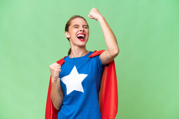 Junge kaukasische Frau mit isoliertem Hintergrund im Superheldenkostüm und feiert einen Sieg - Foto, Bild