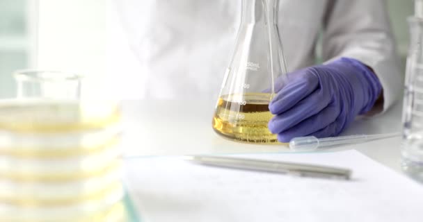 Chemik wlewa olej jadalny i produkty naftowe do kolby z bliska. Analiza ropy naftowej - Materiał filmowy, wideo