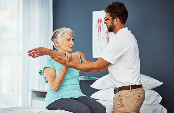 Ressens quelque chose. une femme âgée qui travaille pendant son rétablissement avec un physiothérapeute masculin - Photo, image