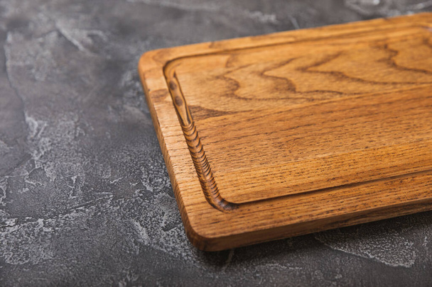 台所の黒いテーブルの上に空の木製の板。キッチンタオルでボードを切断。木製のまな板、コピースペース。台所用品だ。レシピだ。テキスト用の場所。平敷. - 写真・画像