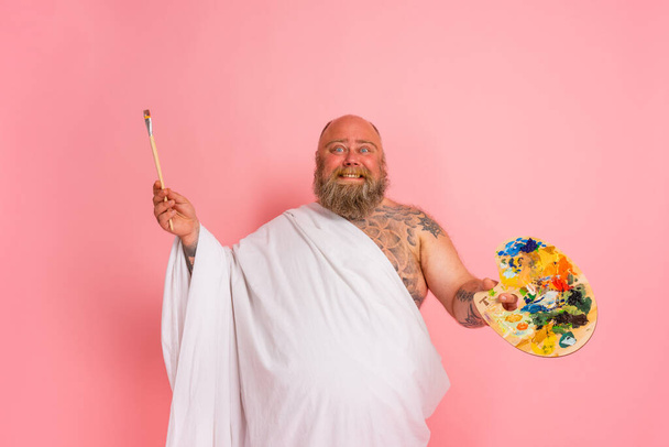 Fat man acts like an important artist with brush in hand - Photo, Image