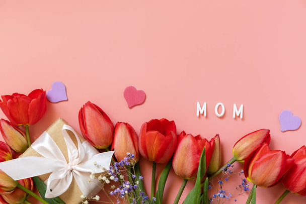 Дар-боксер з луками маленьких сердець і червоних тюльпанів на рожевому тлі з порожнім простором. Святкування Дня матері. Вид згори. - Фото, зображення